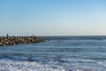 Beach at Castlecliff with. rock groyne breakwater projecting into sea with fishers