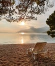 Beach chair on a pebble beach against the background of a calm clean sea, mountains and sunset.  Summer vacation at sea Royalty Free Stock Photo