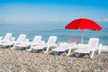 Beach chairs and red umbrella on shingle beach Royalty Free Stock Photo