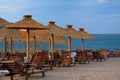 Beach chairs and straw umbrellas on tropical resort. Line of lounge chairs. Blue sea and sky on background. Summer vacations Royalty Free Stock Photo