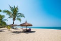 Beach chairs, umbrella and palms on sandy beach near sea.