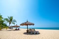 Beach chairs, umbrella and palms on sandy beach near sea. island in Phuket