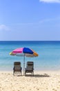 Beach chairs under colorful umbrella on the sand beach looking at the clean blue sea Royalty Free Stock Photo
