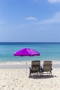 Beach chairs under pink umbrella on sand beach with beautiful blue sea and clear blue sky view Royalty Free Stock Photo