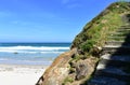 Beach with cliff, white sand, waves and stairs. Blue sky, sunny day, Lugo, Spain. Royalty Free Stock Photo