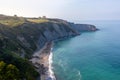 Beach and cliffs by the ocean at sunset. Small house on top of the hill at sunset time. Hidden beach at the botton of a cliff.