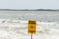 Beach closed sign. Despite the warning people are still swimming and surfing. Selective focus on Royalty Free Stock Photo