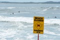 Beach closed sign. Despite the warning people are still swimming and surfing. Royalty Free Stock Photo