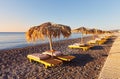 Beach with comfortable sun loungers and umbrellas by the sea at sunrise