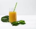 Beach concept with orange juice, straw, sunglasses, monstera leaf