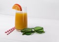 Beach concept with orange juice, straw, sunglasses