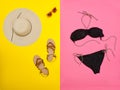 Beach concept. Women`s hat, sandals, black swimsuit, glasses. Yellow with pink background, top view Royalty Free Stock Photo