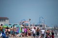 Beach crowded with people on a sunny cloudless day. A female lifeguard is seen laying on the roof of a lifeguard stand looking out