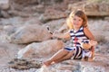 Beach cute girl posing on a rocky beach barefooted with curly hair wearing sailor dress and sun glasses Royalty Free Stock Photo