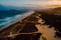 Beach with dunes, ocean and town with sunset lights in Florianopolis