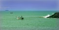 Beach with fishermen wooden motor boat and ship.