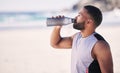 Beach, fitness and man drinking water after running, workout or cardio exercise on mockup space. Hydration, drink and Royalty Free Stock Photo