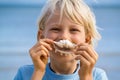 Beach fun, cute child holding shell over his mouth