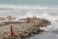 Beach of Gelendzhik resort. Storm waves break on breakwaters made of large rocks. People stand on the breakwaters