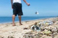 A man casually throws garbage on the ground, adding to the large amount of litter at the beach