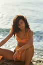 Beach Girl Model in Orange Bikini on the Rocky Deserted Seashore During Summer Beach Holidays Royalty Free Stock Photo