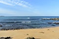 Beach with golden sand, rocks and blue sea with small waves and foam. Sunny day, blue sky. Galicia, Spain. Royalty Free Stock Photo