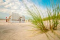Beach Green grass and Beach cabins on white sand on the sand dunes in the wind.Beach summer background.Summer mood. Royalty Free Stock Photo