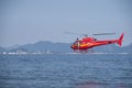 A beach guard firefighter helicopter flies over the sea near Ipanema Beach, Brazil. In the background sugar loaf mountain and