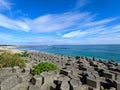 A beach half-filled with tetrapod and sandy at the other side facing the Pacific Ocean with a lighthouse in sight under Royalty Free Stock Photo