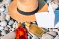 Beach hat on opened book with sunscreen and shoes on pebble beach Royalty Free Stock Photo