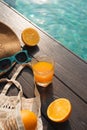 Beach hat, orange juice and sunglasses near the swimming pool Royalty Free Stock Photo