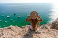 Beach holidays. A hot beautiful woman in a sun hat and a white bikini, sitting with her hands raised to her head Royalty Free Stock Photo