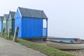 Beach huts and fishing boat on English seaside on a foggy day Royalty Free Stock Photo