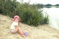 The beach at the lake in the sand a little girl in a hat playin Royalty Free Stock Photo