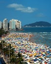 Beach landscape filled with many tourists and umbrellas on a summer day