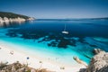 Beach leisure activity. Fteri bay, Kefalonia, Greece. White catamaran yacht in clear blue sea water. Tourists on sandy