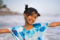 Beach lifestyle portrait of young beautiful and happy Asian child girl 8 or 9 years old with cute double buns hair style playing Royalty Free Stock Photo