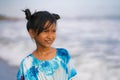 Beach lifestyle portrait of young beautiful and happy Asian child girl 8 or 9 years old with cute double buns hair style playing Royalty Free Stock Photo