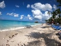 Beach line with white sand, blue lounge chairs fluffy clouds and tall palm trees Royalty Free Stock Photo