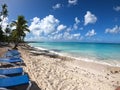 Beach line with white sand, blue lounge chairs fluffy clouds and tall palm trees Royalty Free Stock Photo