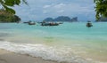 Beach with long tale taxi boats in turquoise water and mountains on the background