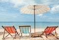 Beach lounge chairs under umbrella on beach.