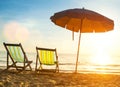 Beach loungers on deserted coast sea at sunrise.