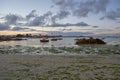 Beach at low tide during dusk, sand and seaweed, little boats, cloudy sky, romantic mood, idyllic Royalty Free Stock Photo