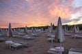 a beach with many tables and chairs and umbrellas on it at sunset or dawn with a pink sky