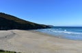 Beach with morning light. Golden sand, rocks and blue sea with waves and foam. Clear sky, sunny day. Galicia, Spain. Royalty Free Stock Photo