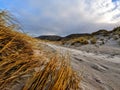 Beach with mountains and brown grass and beach sand with louds and blue sky and valley