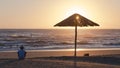 Beach Ocean Shoreline  Man Sitting Umbrella Silhouetted Sunrise Royalty Free Stock Photo
