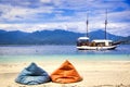 Beach paradise island in Indonesia. Two big colorful cushions for guests in the foreground. In the distance the turquoise sea and