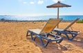 Beach with parasol and chaise longues by the sea